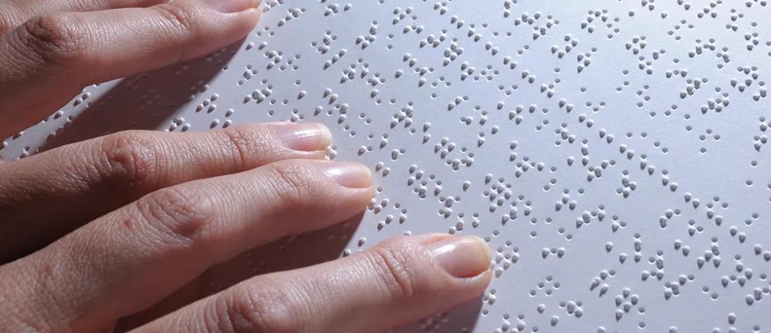a hand reading on braille print paper